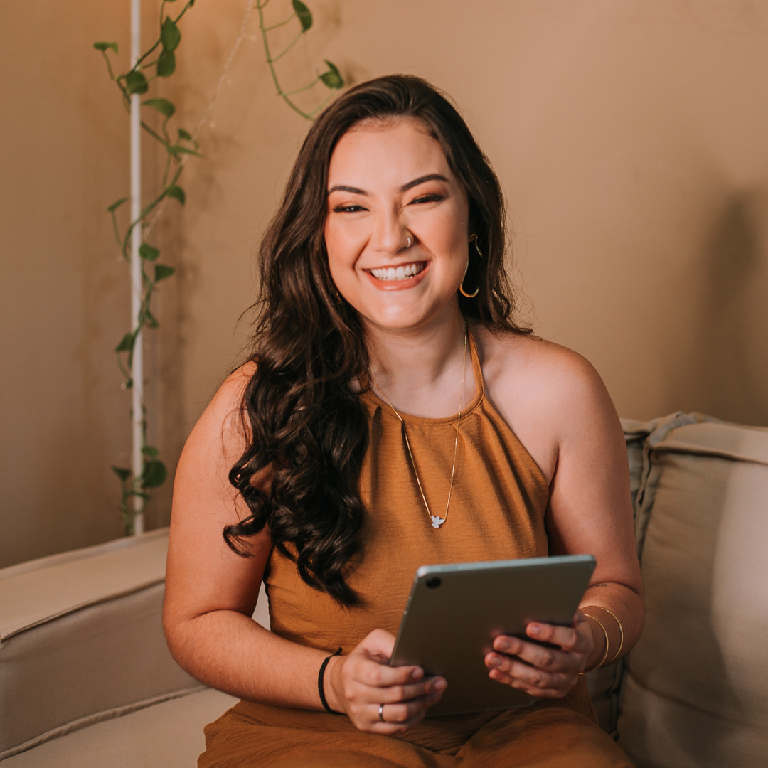 Carolina Alves em atendimento online, sorrindo com um tablet nas mãos