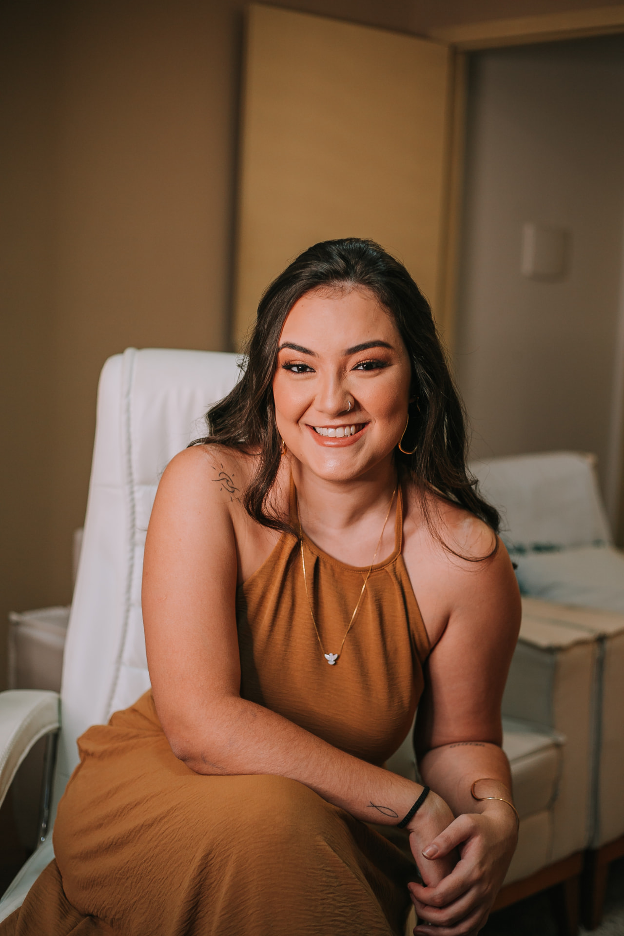 Carolina Alves, psicóloga materna e perinatal, sorrindo em sua poltrona de atendimento
